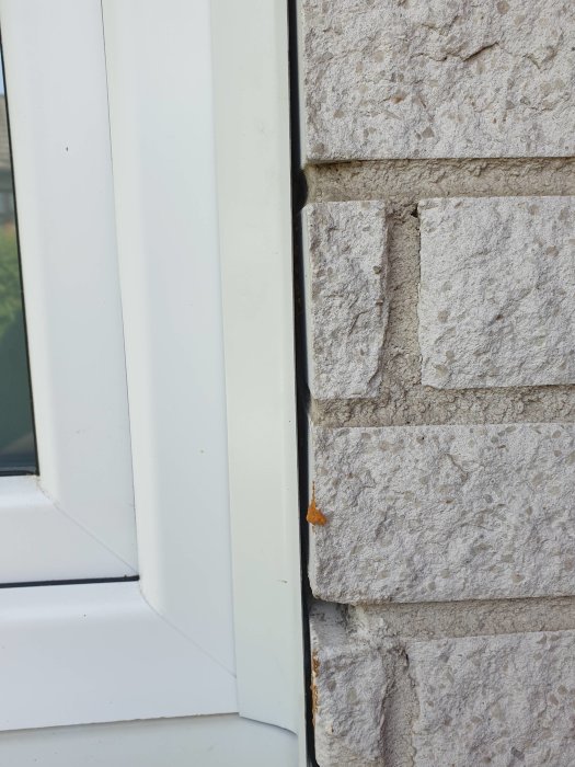 Ej korrekt utfört plåtarbete vid PVC-fönsterinstallation nära stenvägg.