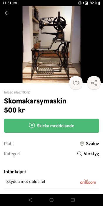 Gammal skomakarsymaskin i gjutjärn mot en vit vägg på ett rutigt golv.