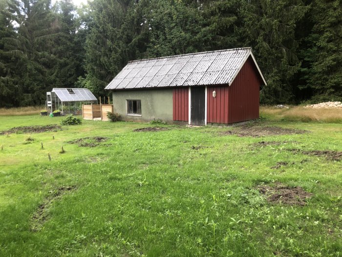 Ett gammalt stall med röda plankor och grå betongväggar omgivet av grönt gräs, planeras omvandlas till gästhus.