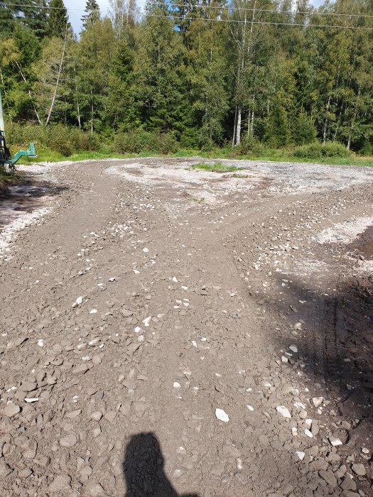 Nygrusad vändplats anlagd inne på en skogsplätt med ledningsgata och synlig skugga av fotografen.