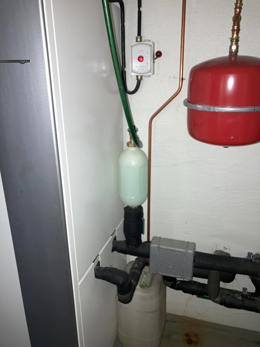 Värmesystem med plastdunk, säkerhetsventil och expansionskärl där vatten läcker in.