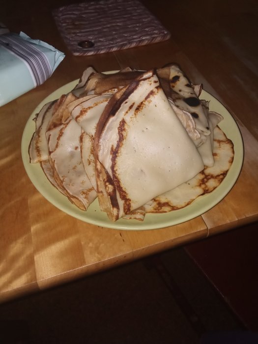 Ett stort fat med hemlagade pannkakor redo för familjelunch.