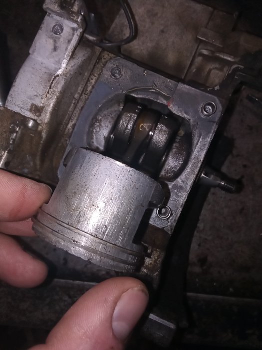 Hand håller en skadad kolvdelen av en Stihl 480k motorsåg med synliga slitage- och skademärken.