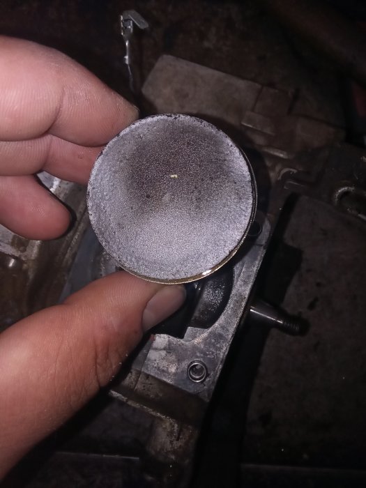 Sliten kolvpiston hållen av en hand, med synliga skador från ett motorhaveri i en Stihl 480k såg.
