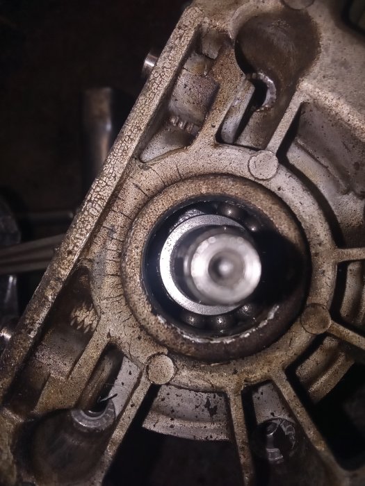 Öppen motorsåg visar ett skadat svänghjul och lager, med slitna komponenter och oljerester, tecken på totalt haveri.