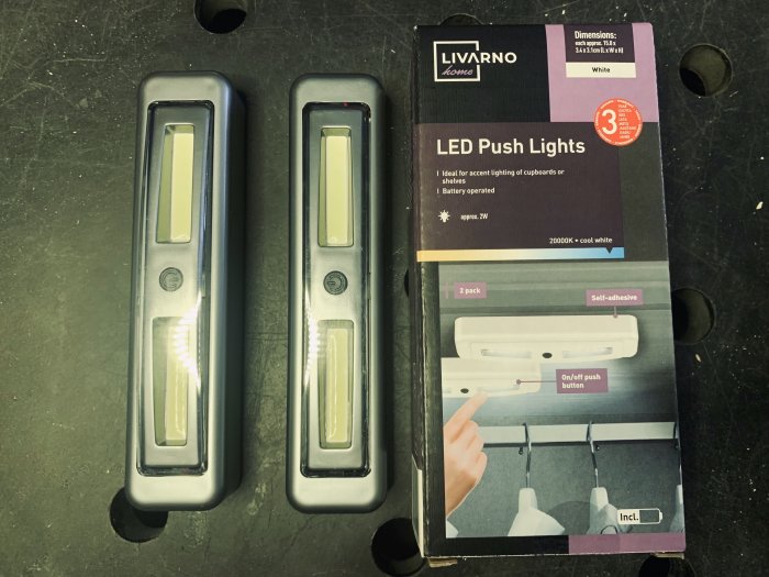 Två LED Push Lights från Lidl på arbetsbänk bredvid förpackningen, batteridrivna och självhäftande design.