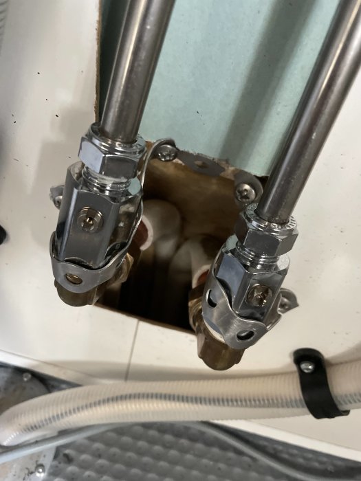 Rörinstallation med metallklämmor genom vägg, synliga rör och kablage.