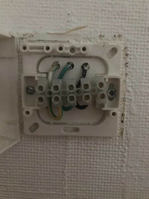 Öppen eldosa med lösa kablar och tejp, i behov av elektrisk åtgärd.