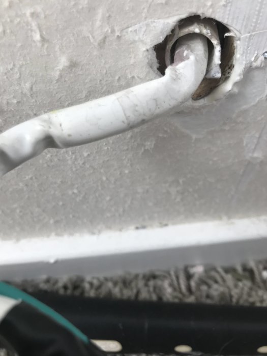 Elledning som går genom ett hål i en vit vägg, tecken på slitage och behov av åtgärd.