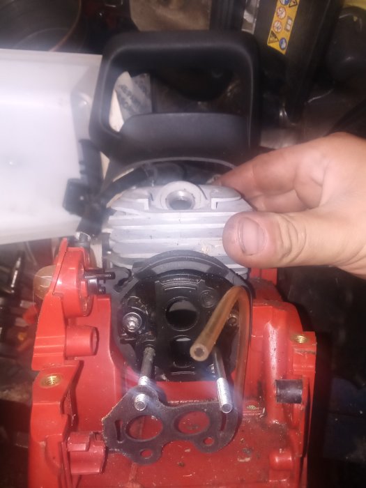 Hand som håller en tändstiftshatt över en motors tändstiftsbrunn.