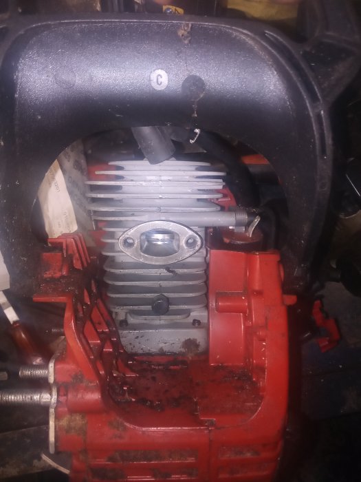 Närbild på en röd och svart motors kylvätska och insugningsdelar, smutsig och använd.