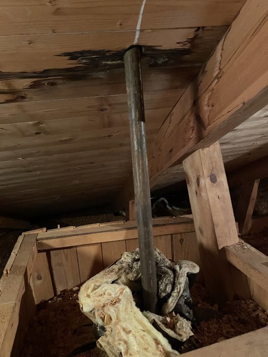 Eternitventilationskanal och skadad isolering i husets vindutrymme.