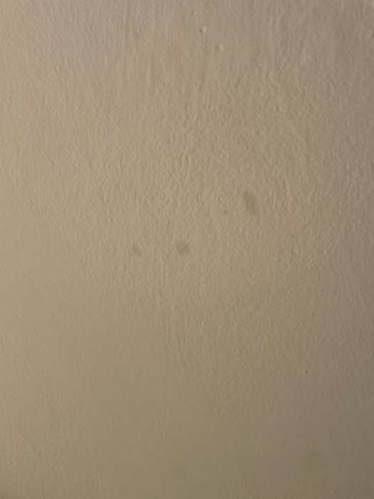Närbild på en vägg med sprickor och märken, tecken på eventuella strukturella problem.
