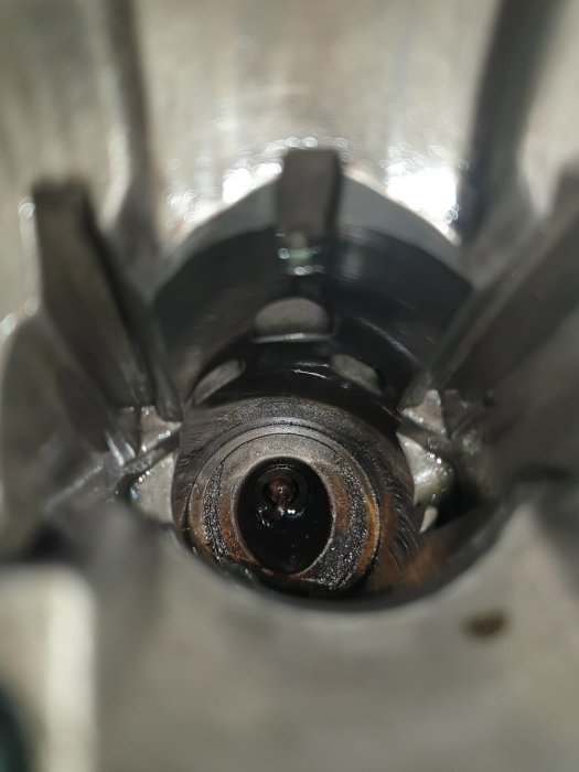 Närbild inuti cylinder med synliga mekaniska delar och återspeglingar på metallytan.