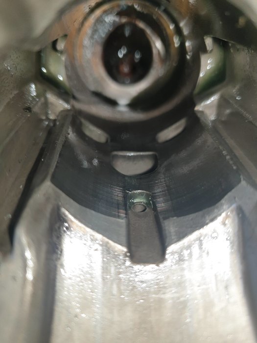 Närbild inuti en cylinder med fokus på dess inre komponenter och strukturer, där ljus reflekterar på de metalliska ytorna.