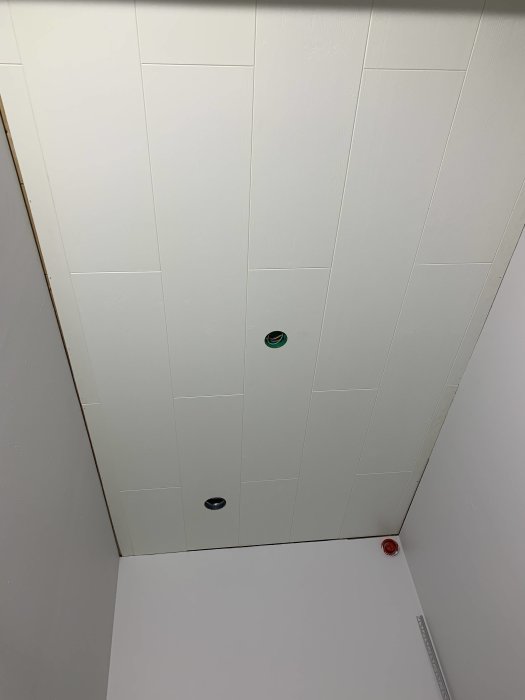 Nyinstallerat vitmålat innertak i klädkammare med synliga väggar och takspotlights.