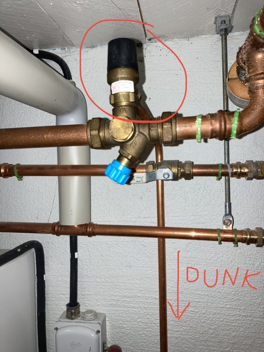 VVS-installation med markerad ventil som orsakade läckage, omgiven av kopparrör.