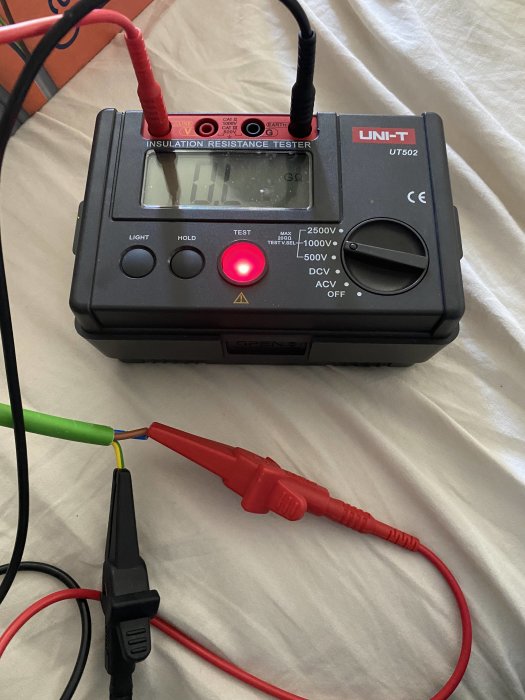 Isolationsresistansmätare UNI-T UT502 kopplad till en elektrisk kabel för testning.