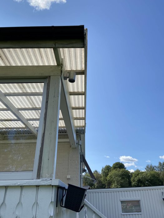Spotlight monterad i takfoten på en altan mot en klarblå himmel.