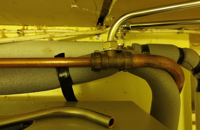 Kopparrör med olika kopplingar och avlängningar som syns under en renoverad installation, möjlig orsak till lägre vattentryck.