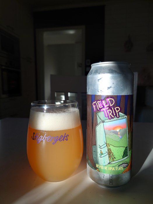 Ölglas med oklar dryck bredvid en burk märkt "Field Trip Kveik IPA" i motljus.