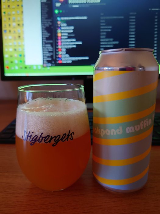Ett glas öl bredvid en ölburk med texten "Duckpond muffin", framför en datorskärm.