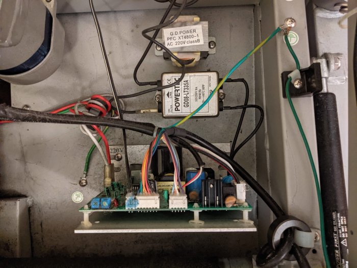 Inre komponenter i ett löpband, inklusive styrkort, transformator och filter, med synliga kablar och elektriska anslutningar.