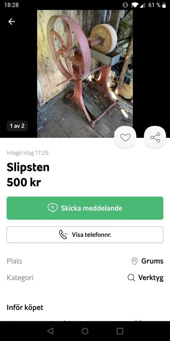 Gammal manuell slipsten med röd ställning i ett skjul.
