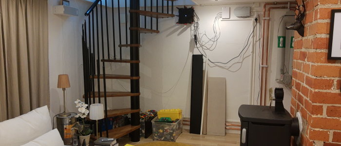 Modern spiraltrappa i vardagsrum med tegelvägg och inredningsdetaljer.