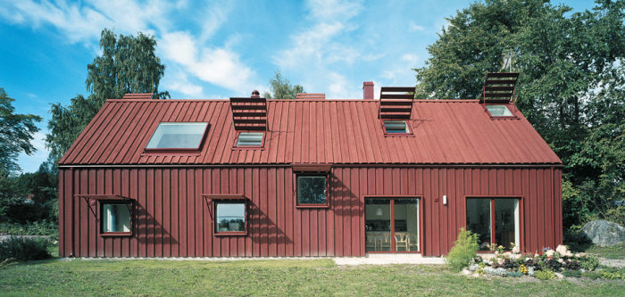 Rödfärgat hus med två våningar och faltak med 45 graders vinkling och synliga falor.