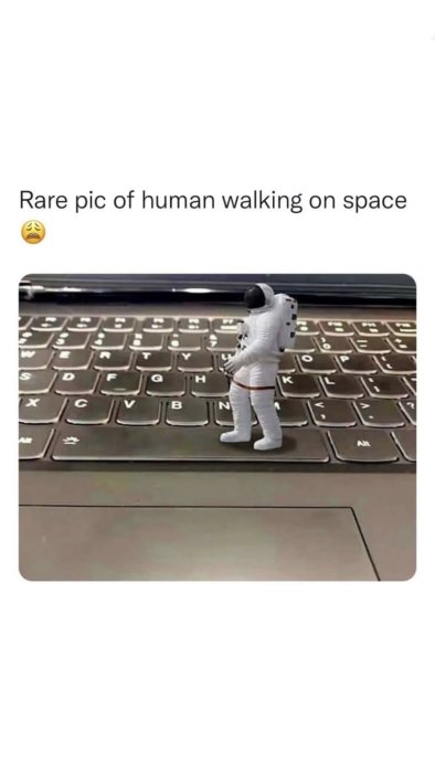 Leksaksastronaut som går på tangentbord som liknar månens yta.