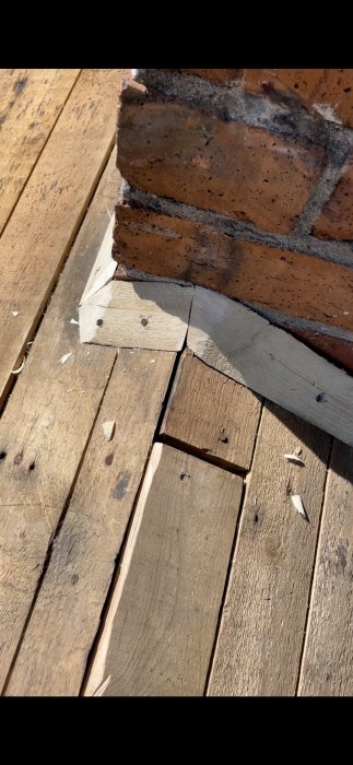 Närbild av en skorstensgenomföring på tak med trälist och tegelstenar.