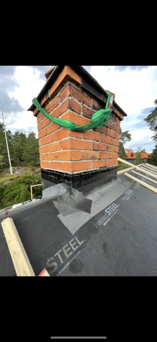 Skorsten med ny lagd skorstensgenomföring utan underbeslag, säkrad med spännband, på tak med Mataki Haloten underlagsduk.