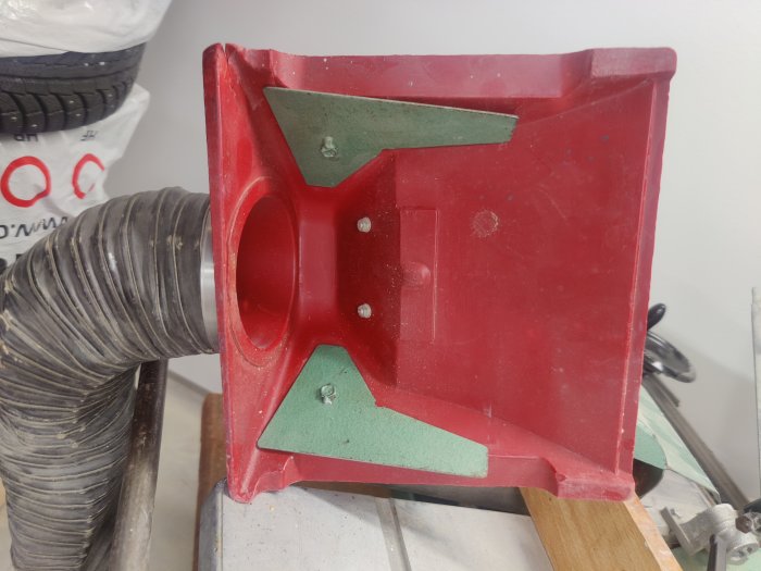 Röd och grön dammsugarmunstycke på en arbetsbänk, vilket ser ut att användas för ett bygg- eller renoveringsprojekt.