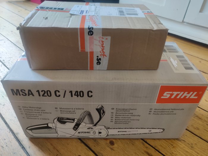 Stängt STIHL-paket och ett mindre paket ovanpå ett trägolv, kopplat till att vara "Stihlig" vid röjning.