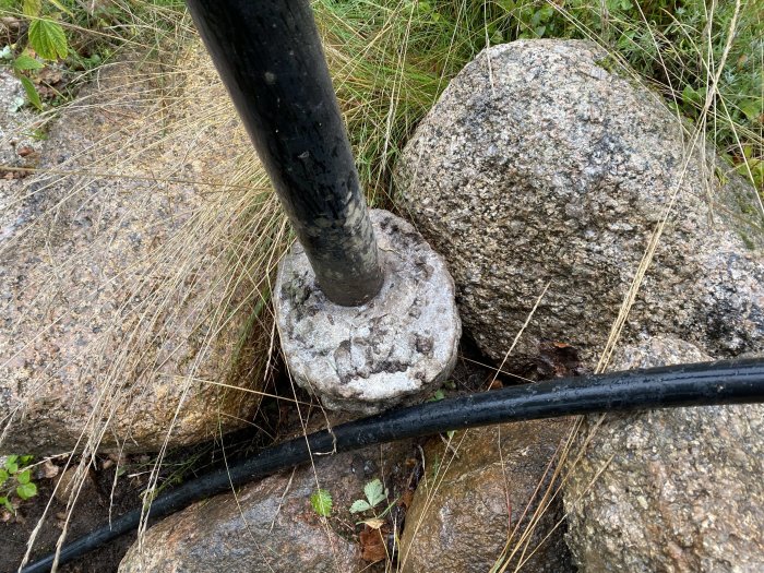 En stolplykta monterad på en gammal betongklump omgiven av gräs och stenar, redo för omgjutning.