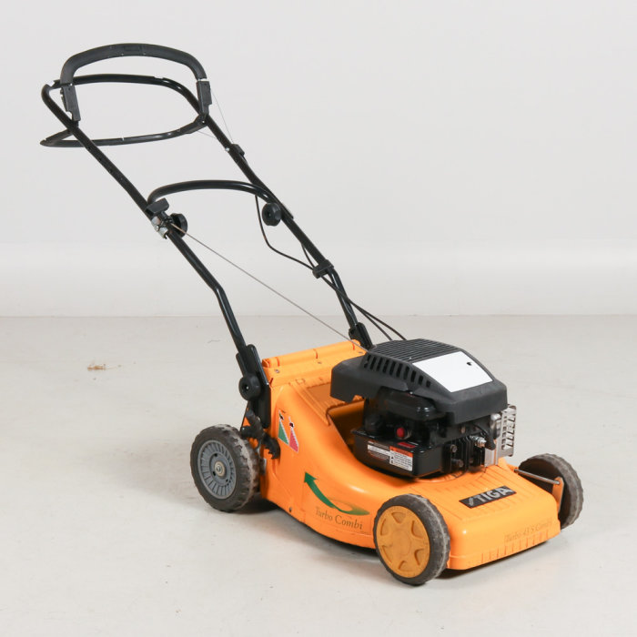 Orange gräsklippare av märket Stiga Turbo Combi på en vit bakgrund.