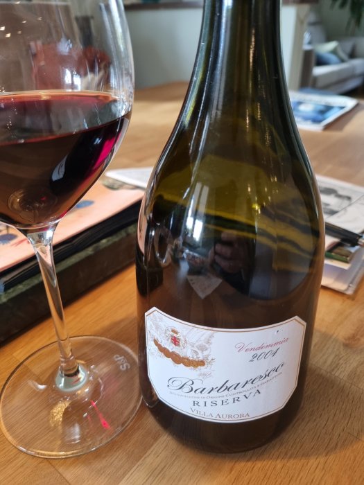 Flaska Barbaresco Riserva vin på bord tillsammans med ett glas rött vin.