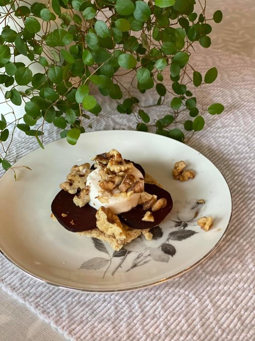 Hemgjord dessert med glass och choklad på tallrik, toppad med valnötter, intill en växt.