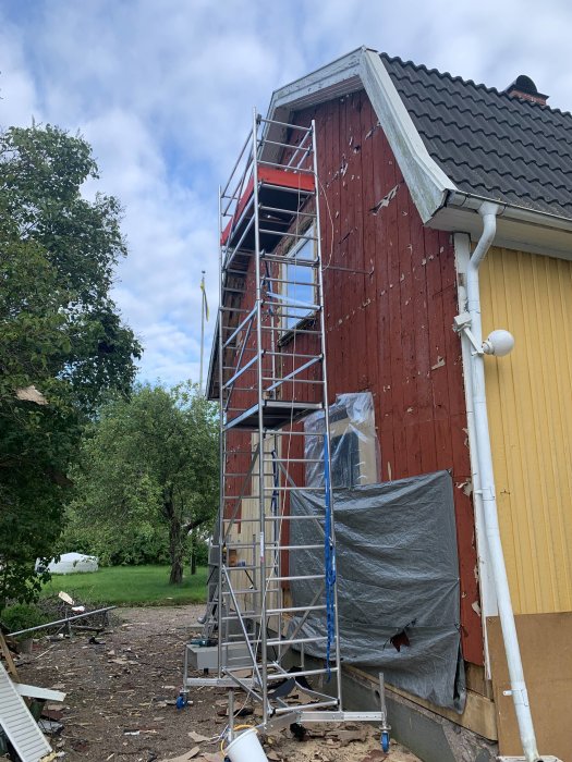 Renovering av 30-tals hus med ställning mot timmervägg och pågående tilläggsisolering.