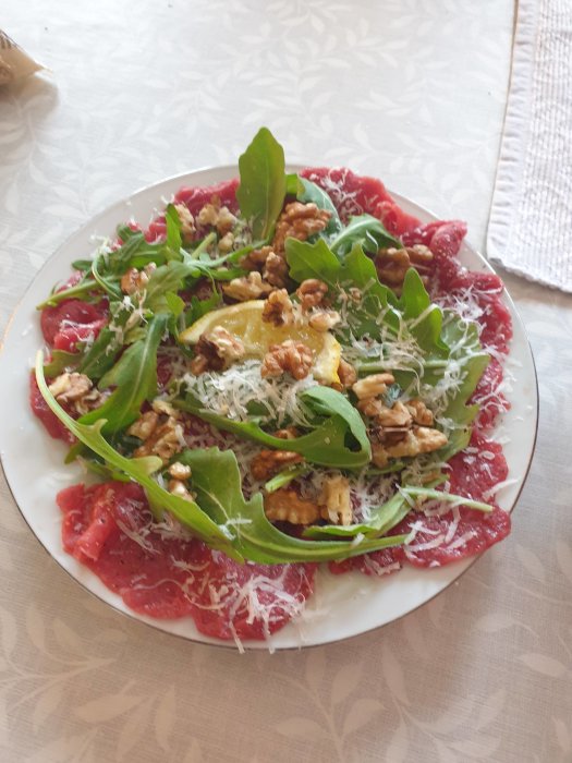 Tallrik med förrätt bestående av carpaccio, rucola, valnötter och riven ost.