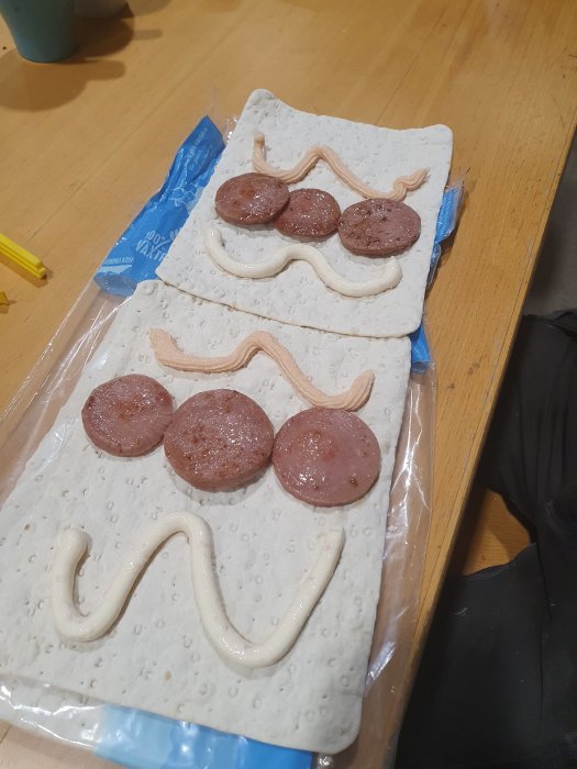 Tunnbröd med strängar av baconost och kaviar samt skivor av stekt falukorv.