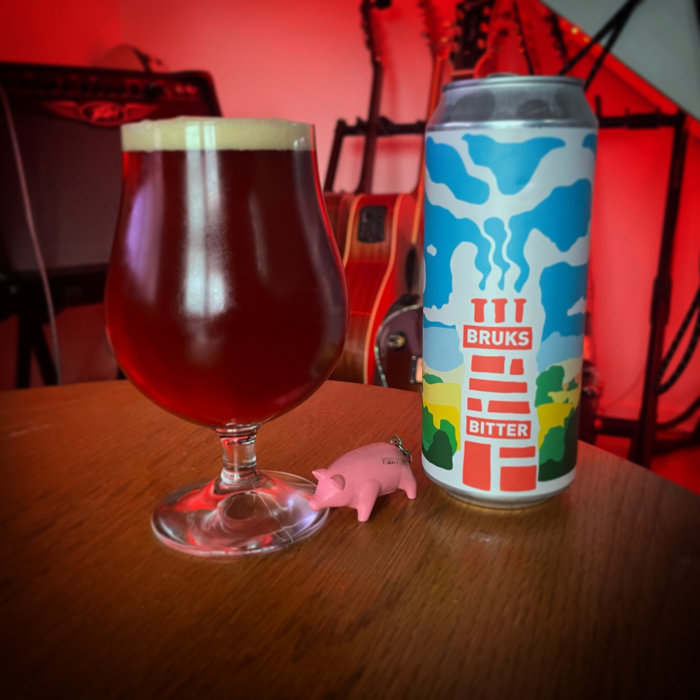 Ett glas bärnstensfärgad öl och en färgglad ölburk med texten "BRUKS BITTER" framför elgitarrer.