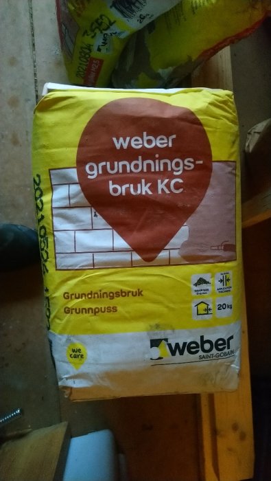 Säck med Weber grundningsbruk KC på ett byggarbetsplatsgolv.