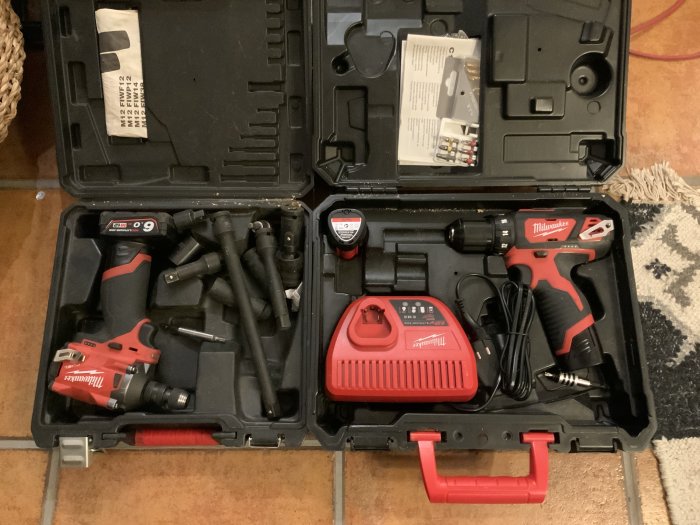 En öppen verktygslåda med Milwaukee M12 skruvdragare, mutterknack, batterier och adaptrar.