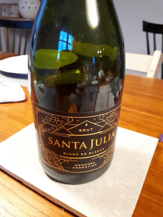 Flaska av Santa Julia Blanc de Blancs Brut på ett bord, rekommenderad för en regnig fredag.