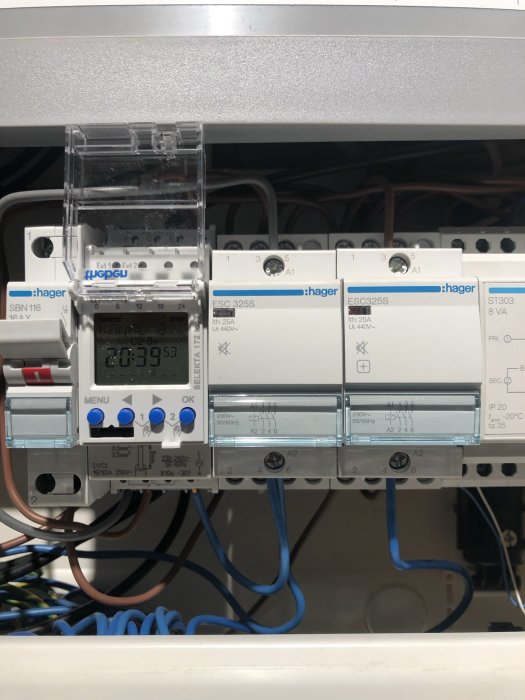 Elcentral med ett tidur och flera reläer, kablar anslutna till plintar, inomhusbelysningskontroll.