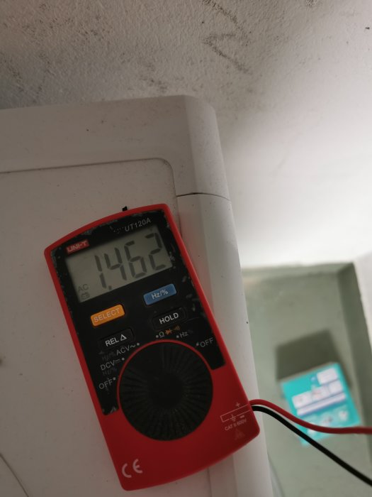 Multimeter visar 146.2V mellan jord och fas i ett vägguttag med otydlig bakgrund.