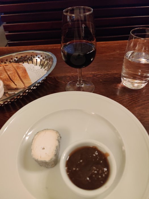 Ostbit med kex och portvin på bord, ackompanjerat av ett vattenglas.