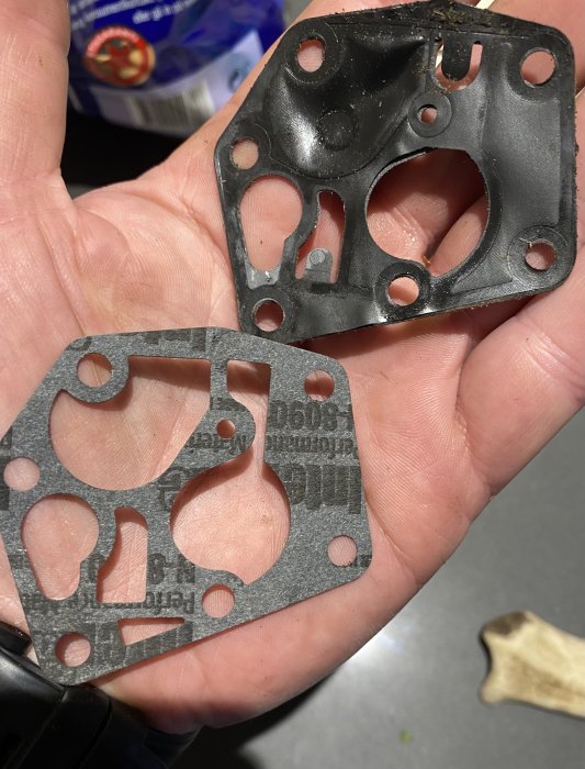 Hand håller ett gammalt och ett nytt bränslepumpsmembran.